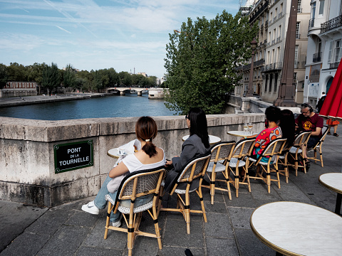 Paris, France - August 14, 2023: People relax by the Seine River in Paris.