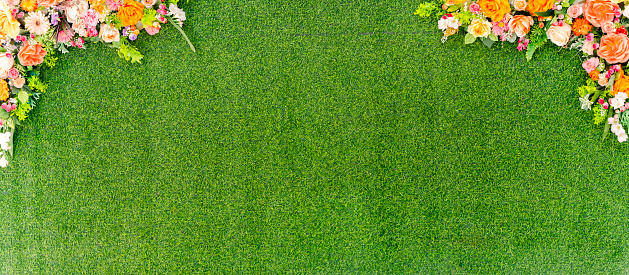 A bouquet of flowers is arranged in a row on a green lawn. The flowers are a variety of colors, including red, yellow, blue, and purple. The flowers are surrounded by green grass. Free space.