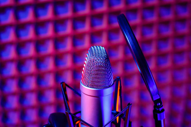 istock Professional studio microphone against acoustic foam panel background in neon light 1975076077
