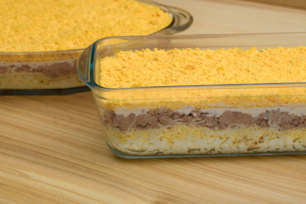 Beautiful layered salads with eggs and tuna in glass bowls close up