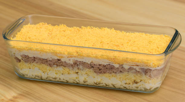 Isolated layered salad with eggs, cheese and tuna for Easter in a glass salad bowl