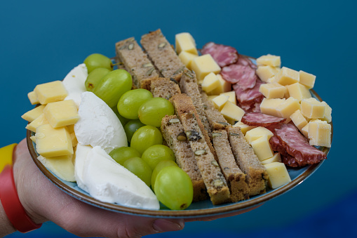 A cheese plate with fruit and cold meats in the form of a buffet