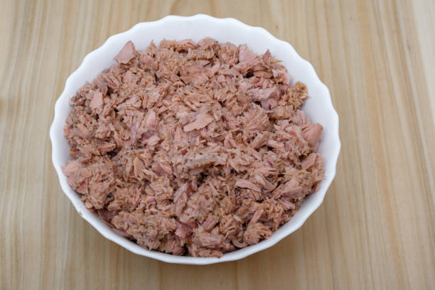 Tuna pieces shredded in a white bowl close up, a lot, isolated