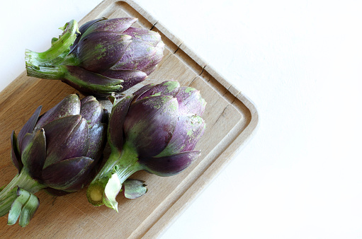 Fresh organic artichokes on wooden background. Healthy and vegetarian food. Overhead view.