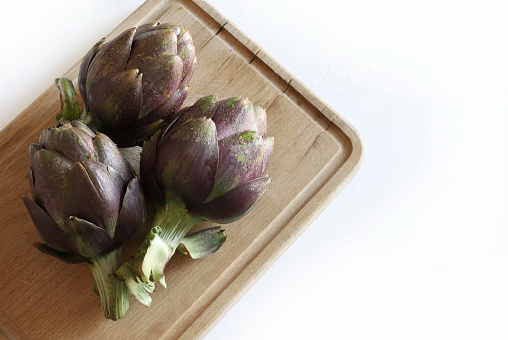 Fresh organic artichokes on wooden background. Healthy and vegetarian food. Overhead view.