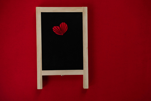Empty black board with heart shape isolated on dark red colour background, Valentines day background