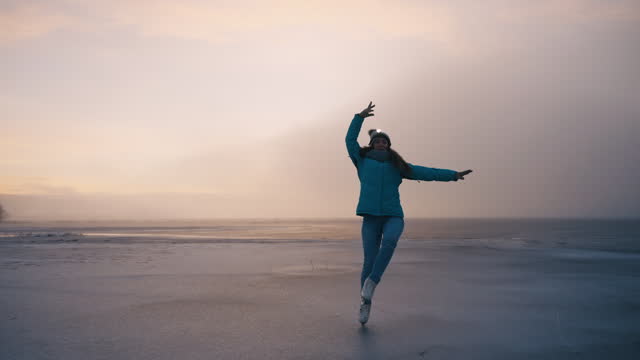 SLO MO Young Woman in Warm Clothes Figure Skating on Frozen Lake in Foggy Weather at Sunrise