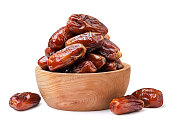 Dates fruits in a wooden plate and scattered close-up on a white background. Isolated