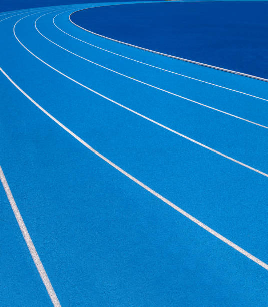 Blue Olympic track lanes with white stripes, an empty background suitable for copy space, represent the concept of physical sports and running, symbolizing commitment and pathways towards goals