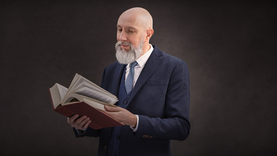Head and shoulders portrait of bald and bearded senior man writing a journal