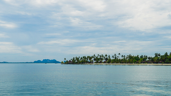 Beautiful beach and Palm trees on Koh Mook island in Thailand. Tropical beach view with white sand and turquoise colored ocean.