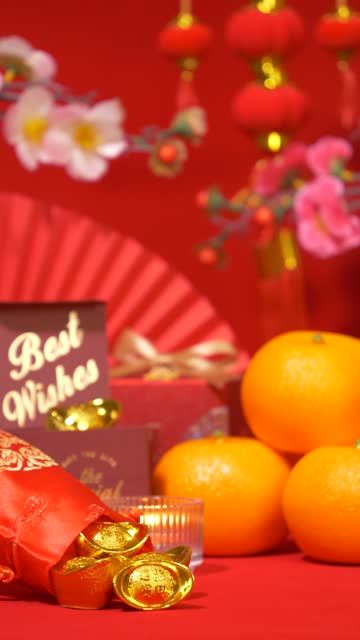 looping vertical of Chinese Lunar New Year background. ancient Chinese gold bar, red gift box with text best wishes, oranges, paper fan, plum blossom branch, candle sway and red paper lantern hanging