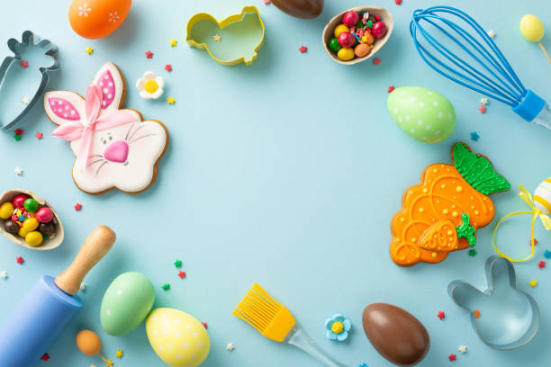 istock Easter baking preparations in confectionery shop. Overhead shot capturing kitchen toolsâwhisk, roller-pin, brush. Charming chocolate eggs and more arranged on light blue backdrop. Empty space for text 1975265825