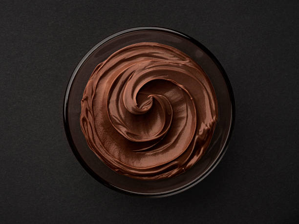 Bowl of hazelnut cream on black background, top view