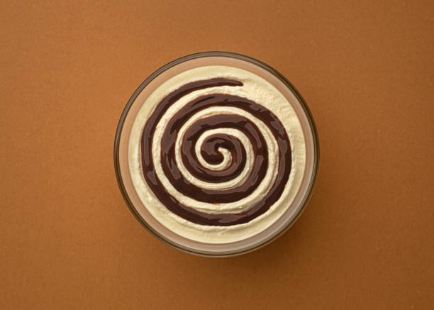 Bowl of sweet cream cheese with chocolate cream swirl on brown background with copy space, top view