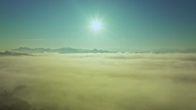 Aerial hyper lapse view The beautiful sky full of mist shines through the mountain range in the morning.  amazing sun shine above the sea of mist.