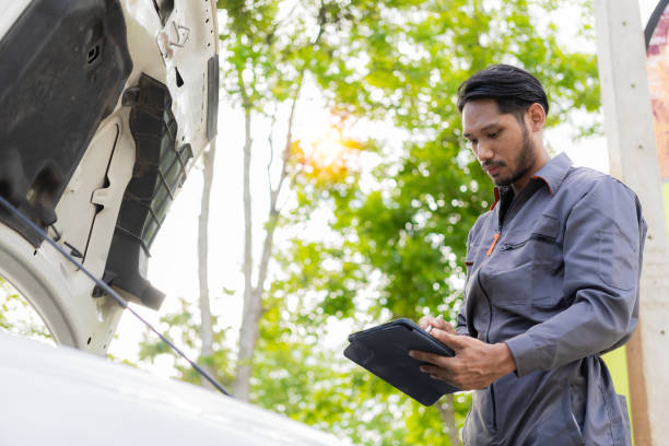 istock maintenance concept Asian auto mechanic or smith writing on clipboard at warehouse workshop Technician making checklist for car repair Roadside breakdown and insurance concept 1975324030