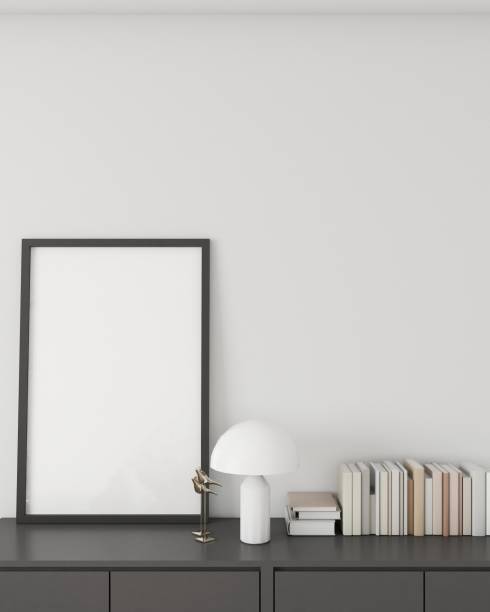istock Minimalistic interior design featuring a modern sideboard with a framed blank poster, a stylish white mushroom lamp, and a neatly organized row of books, against a clean white wall. 3D render 1975359530