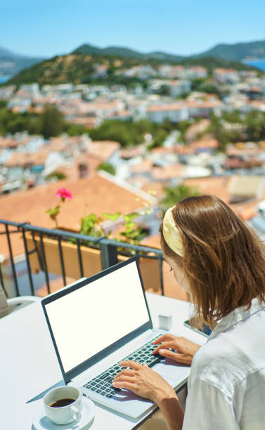 istock Rear view freelancer woman working on laptop computer over Mediterranean view resort 1975392309