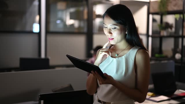 Asian business woman using digital tablet and working late at night