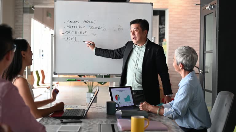 Senior male entrepreneur presenting his business ideas and marketing strategy to his business partners in meeting room