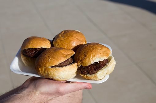 Hamburgers without toppings on a disposable plate to take away food for poor people. Cheap junk food with bun and beef