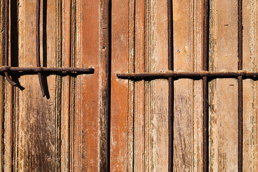 Exterior of an old brown wooden door with rusty ironwork.