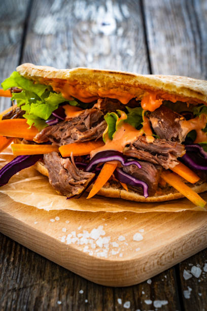 istock Pita - big sandwich with pulled beef and fresh vegetables on wooden table 1975427072
