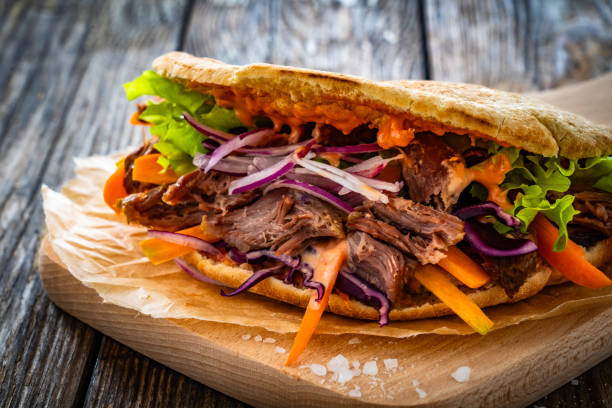 istock Pita - big sandwich with pulled beef and fresh vegetables on wooden table 1975427582