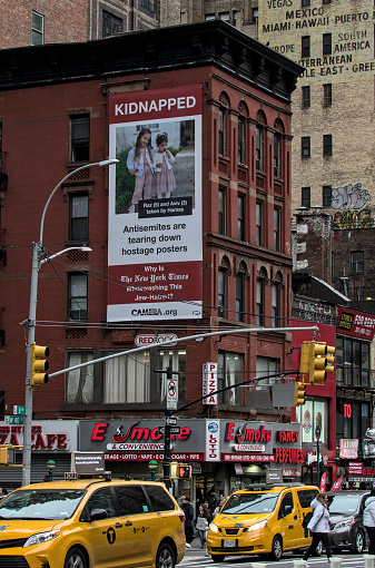 New York, NY - Jan 27 2023: View down 8th avenue in Manhattan near 40th street featuring a political poster referencing the kidnappings as part of the war between Israel and Hamas on a brick building.