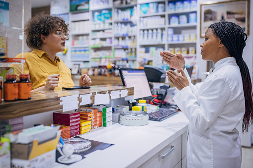 Female pharmacist talking to a woman customer at the drugstore.