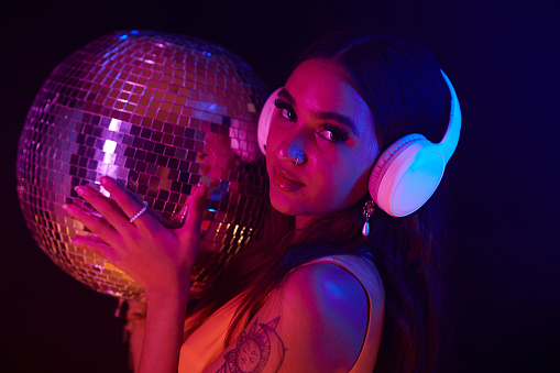 Portrait of club girl in headphones holding disco ball