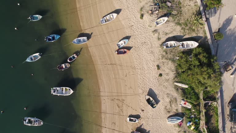 Aerial top down forward over many fisher boats docked on sand beach