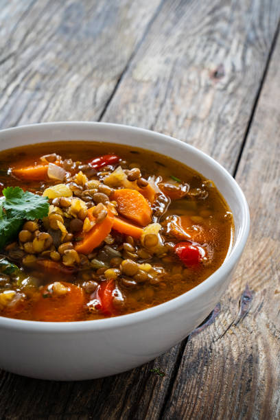 istock Fresh vegetable soup with lentil on wooden table 1975441687