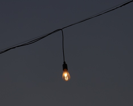 Small electric bulb hanging on the top with the wires photography at Riverfront Park, Ahmedabad. Captured this bulb while travelling in the evening after sunset.