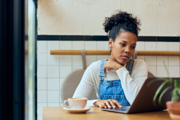 istock An African woman using a laptop while sitting at the cafe, working online. 1975471306