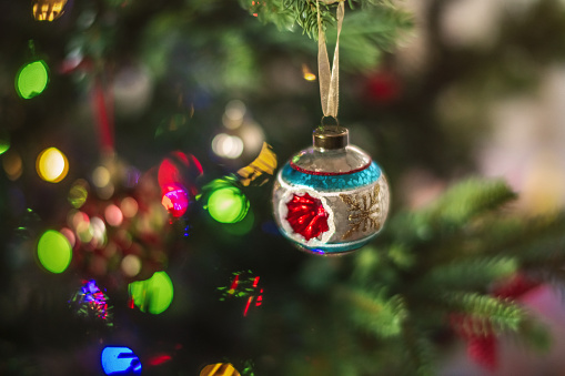 Christmas tree with decorations and lights background, close-up. Hanging vintage ball on pine, lighting garland and ornaments.