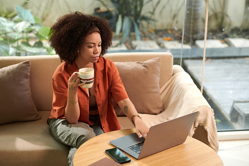 Businesswoman having morning coffee when answering emails from colleagues and customers