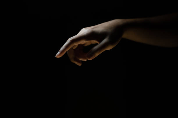 istock Male finger pointing at something. Black background. 1975513363