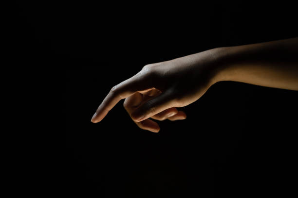 Male finger pointing at something. Black background.