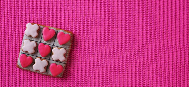 istock A love-themed Tic Tac Toe game set on a pink background, viewed from the top 1975519601