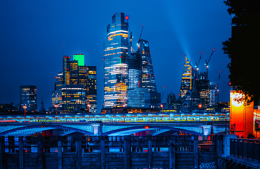 Panoramic view of The City of London cityscape skyline with Blackfriars Bridge and metropole financial district modern skyscrapers after sunset on the night with illuminated buildings with Thames river and cloudy sky in London, UK