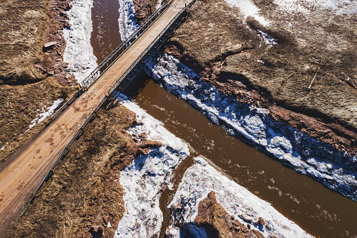 Aerial view of a narrow bridge crossing a tidal river.