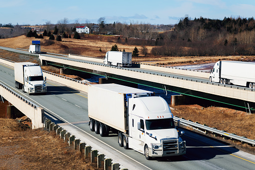 Semi trucks on a highway bridge crossing a tidal river. (Composite image)