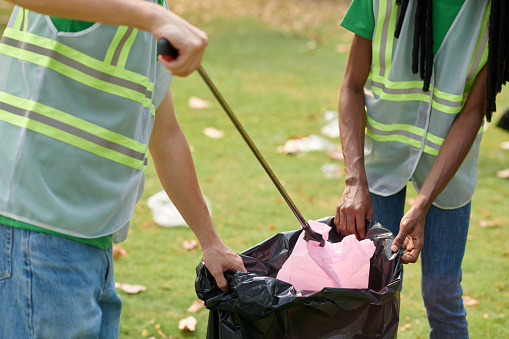 Cropped image of volunteers putting garbage in big bags