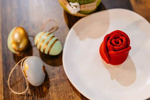 Rose-shaped dessert served on a plate on an Easter-themed table in a café.