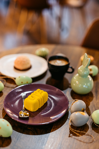 Mini desserts served with coffee on an Easter-themed table in a café. Yellow mini dessert that spells 