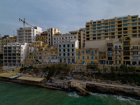 New modern hotels are being build in Xlendi town above pedestrian walkway by the sea. Aerial view. Date: 25.10.2023 Xlendi, Gozo, Malta.