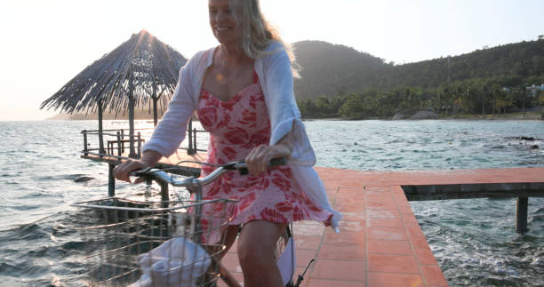 istock Senior woman rides bicycle on pier 1975624000
