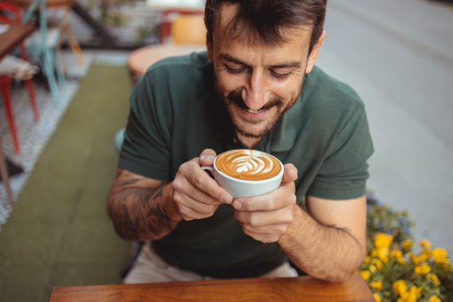 Close up image of young man enjoying the coffee in outside cafeteria